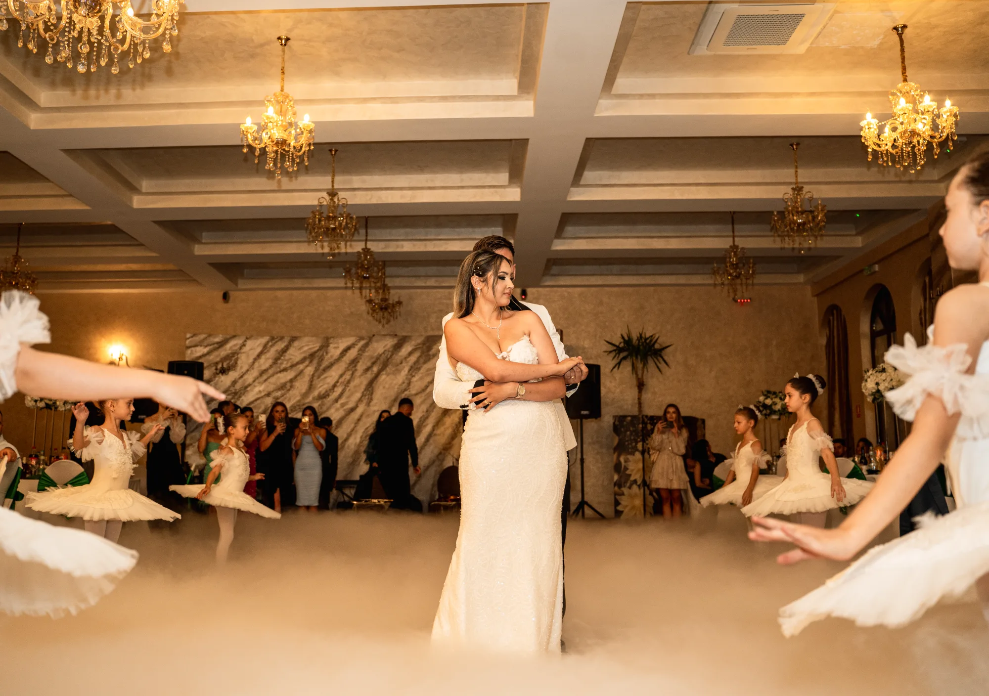 Mirii dansează primul dans într-un ballroom cu candelabre, învăluiți în fum, cu balerine în jurul lor.